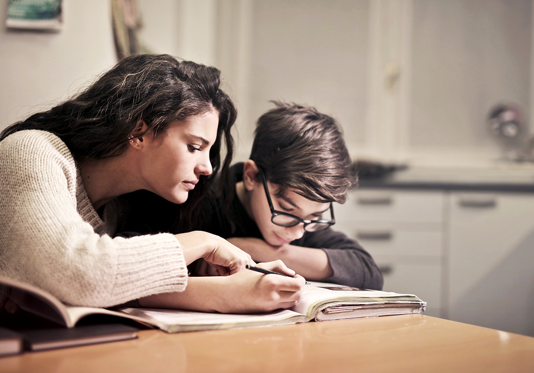 En vuxen som hjälper ett barn med läxläsning.